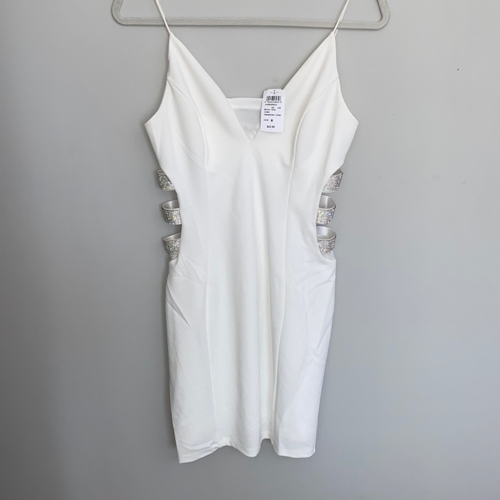 Ivory formal dress, curve complementing side cuts with rhinestones.